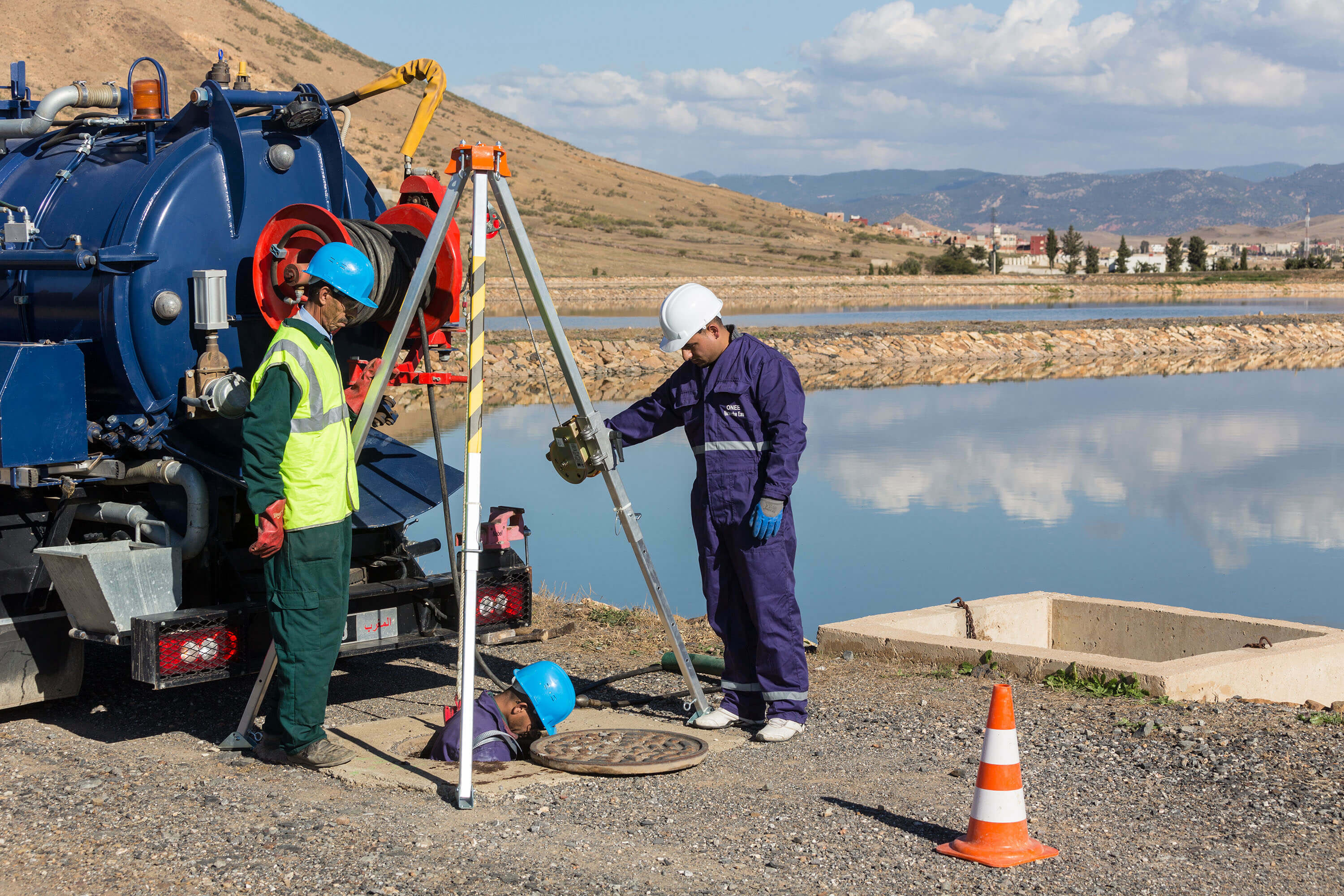 Trois ouvriers contrôlent les égouts à un bassin de collecte d'eau purifiée
