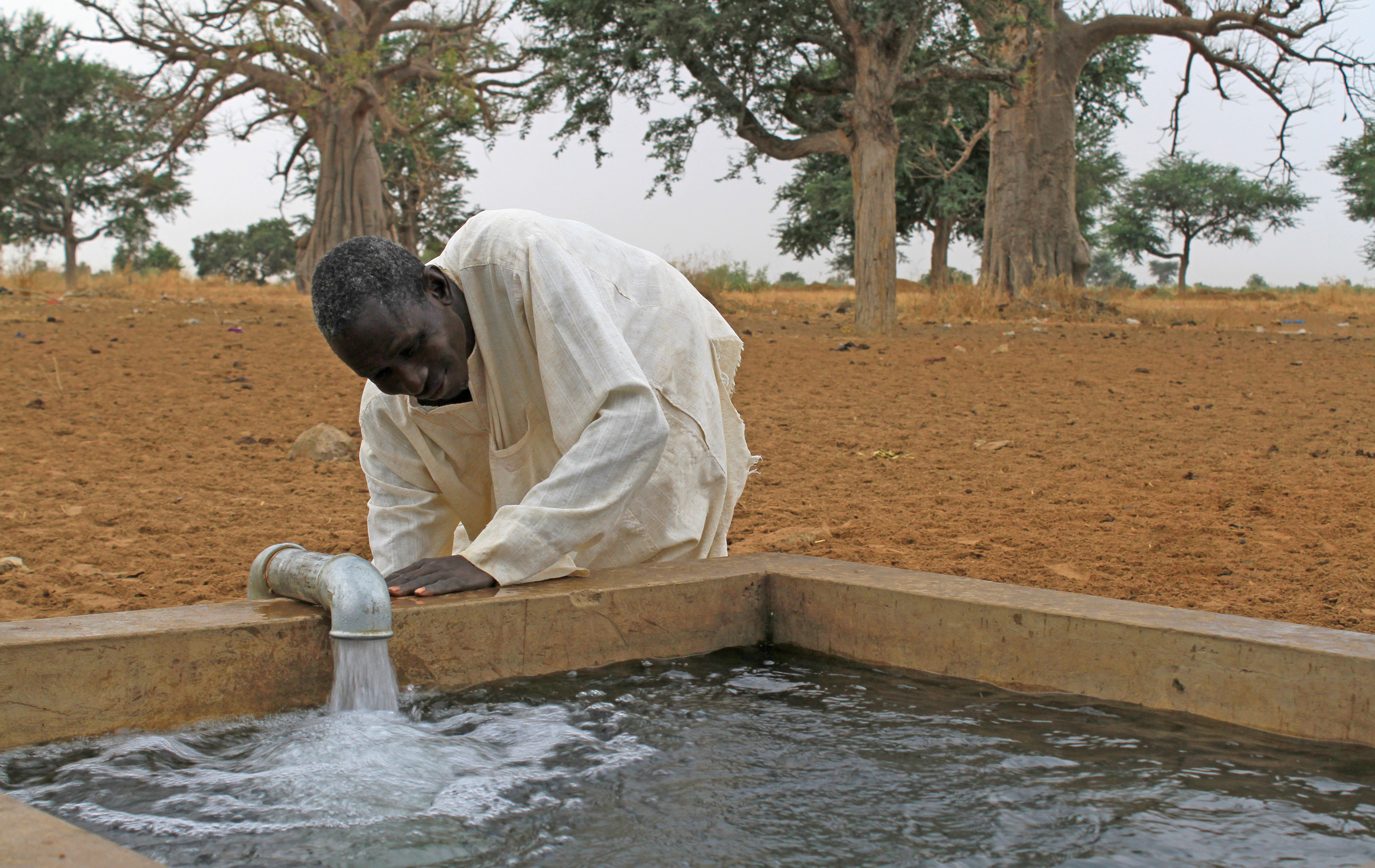 Mann schöpft Wasser am Brunnen