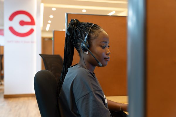 Une jeune femme équipée d’un casque-micro travaille à son poste dans un centre d’appels.